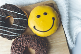 A yellow chocolate donut on a bed