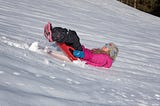 Blonde Lady In Pink Snow Jacket Skating Backwards Downhill In The Snow.