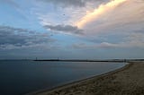 A picture of the Delaware Bay from Lewes Beach at sunset as two birds swoop over the bay.