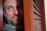 Tucker Lieberman, coming out of the closet, half in shadow, looking surprisey and sneaky