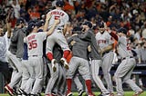 a crowd of red sox players gather in a pile celebrating their win