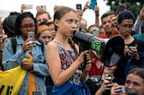 Greta Thunberg speaking in a crowd.