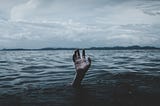 hand reaching up out of dark, gloomy lake