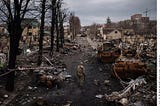 A Ukrainian soldier walks amongst destroyed town and Russian tanks.