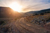 A desert road at sunset, mountains in the background.