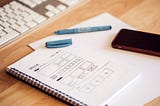 Photo of a notebook with a drawing of a wireframe.