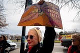 A woman holds up a sign that reads, “Divest from Fossil Fuels.”