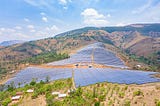 A large solar panel farm extends over a hilly landscape with green vegetation in Mubuga, Burundi harnessing renewable energy from the sun.