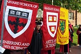 Author posing by Harvard school flags during commencement