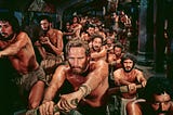 A scene from the 1959 film Ben-Hur in which Charlton Heston in the title role is one of a large group of slaves forced to row a Roman galley.