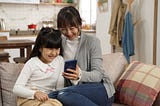 Mother and daughter interacting with a mobile phone together