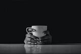 Two hands holding a coffee mug against a black background