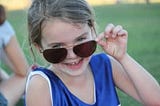 Young girl with oversized sun glasses, laughing.