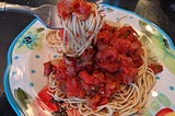 A plate of plant-based spaghetti sauce served over spaghetti noodles.