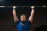 mat fraser warming up with a barbell over his head