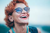 middle-aged woman laughing as she looks up at the sky because she is living her life purpose