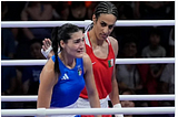 Image shows two women. In blue, looking tearful, Italian boxer, Angela Carini; in red, Algerian boxer Imane Khelif. Imane is reaching out to console Angela.