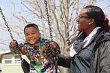 mother pushing child on swing