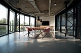 Large conference room full of natural light, with a table and mauve chairs