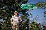 A man with a hat standing near a sign