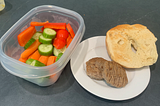 Photo of chopped vegetables, a bagel, and breakfast sausage.