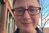 The author is smiling into the camera. He is white and trans. He looks a little tired, but otherwise relaxed. He’s wearing glasses.