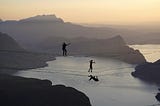 Two people walk over a tight rope, symbolizing the fine line between giving mindfully and overgiving