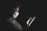 Picture of a woman wearing a mask and using a phone
