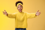 Young lady in a yellow sweater with a warm welcome and outstretched hands