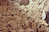 A cardboard box full of tiny trumps: 3" tall cardboard cutout stickers in the silhouette of President Trump, with protest slogans written on the front and instructions on the back