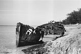 Black and white photo of an old shipwreck on a beach