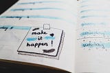 Page of a diary showing an image that reads ‘make it happen’