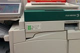 A large Fuji-Xerox photocopier stands in an office