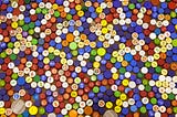 A view from above of a large quantity of bottle caps of different colors places very close to each other