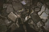 Someone standing over a piles of burnt books and personal things.