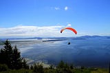 paraglider flying over trees and water clearing their mind