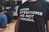 Man wearing a t-shirt bearing the inscription “Good intentions are not enough.”