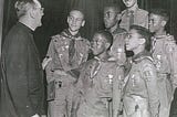B&W photo of five Black boy scouts with their scout master and a white priest.