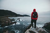7 Powerful Life Lessons From Living Out of 2 Backpacks For Years — man with red jacket standing on lake