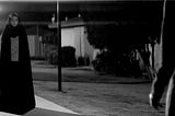 A female vampire wearing a chador stands looking at an unseen character.