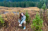 The author kneeling in a meadow with her film camera in Yellowstone National Park