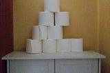 Pyramid of toilet paper rolls with one taken from a middle row.