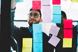 man in glasses posting sticky notes on a window