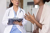 Una persona adulta hablando con un médico en una cita.