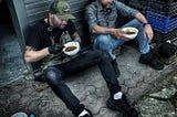 Chef Eric Gephart and Chef Dave White getting a quick bite while cooking for refugees in Poland.