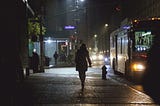 A woman walking alone through a city street at night, symbolizing women’s safety and vulnerability in public spaces.