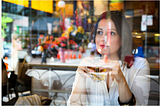 Image of a woman sitting in a cafe staring out of the window