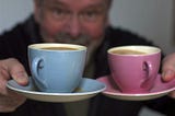 Man holding out two cups of coffee