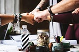 A color picture of a group of people fist bumping in the middle.