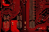 Closeup of circuit board bathed in red light.